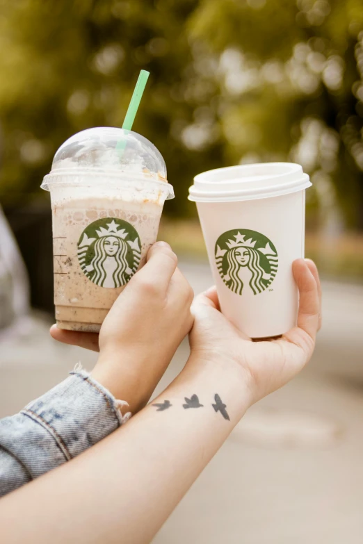 a person holding two cups of starbucks coffee, a photo, by Lucia Peka, trending on pexels, renaissance, temporary tattoo, square, splash image, 2717433015