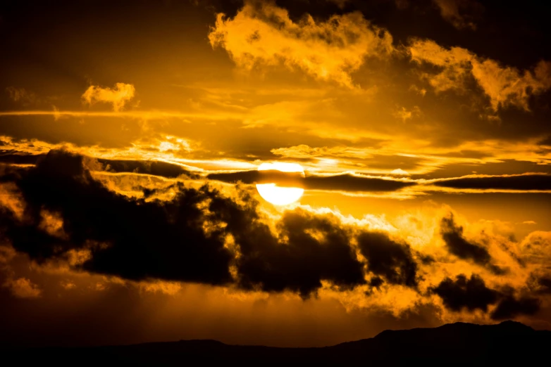 the sun is setting behind the clouds in the sky, by Jesper Knudsen, pexels contest winner, romanticism, yellow, big island, brown, black