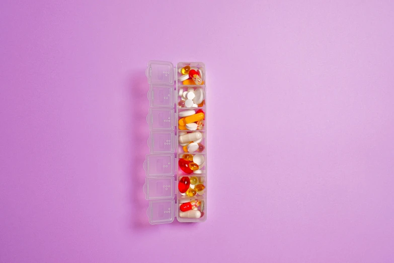 a plastic container filled with assorted pills, trending on pexels, crystal cubism, autumnal, flat minimalistic, white human spine, pink and orange