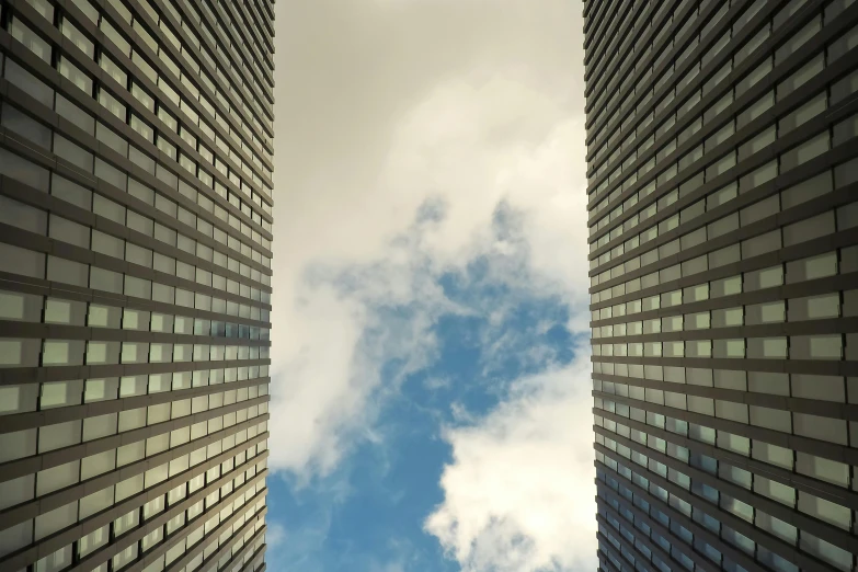 a couple of tall buildings next to each other, inspired by David Chipperfield, pexels contest winner, cloud vortex, square lines, windows, high resolution