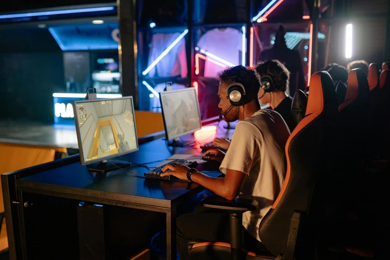 a man sitting at a desk in front of a computer, twins playing video games, in a nightclub, cybertech wear, profile picture 1024px