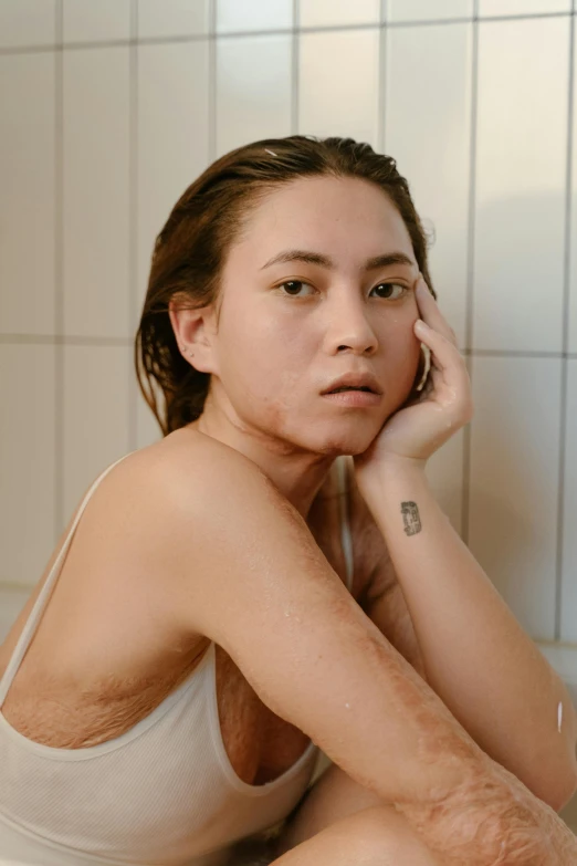 a woman sitting on the edge of a bath tub, inspired by Elsa Bleda, trending on pexels, hyperrealism, face scars, asian face, scales covering her chest, face covered in dirt