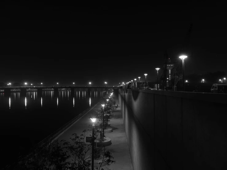 a black and white photo of a city at night, a black and white photo, pexels contest winner, conceptual art, riverside, street lighting, calm lighting, endless night