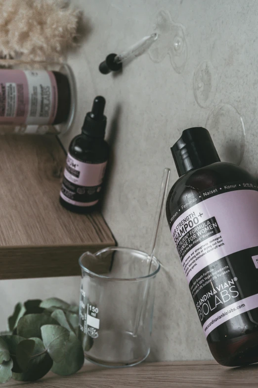 a bottle of liquid sitting on top of a wooden shelf, inspired by Henriette Grindat, unsplash, antipodeans, pink and black, skincare, large jars on shelves, purple accents