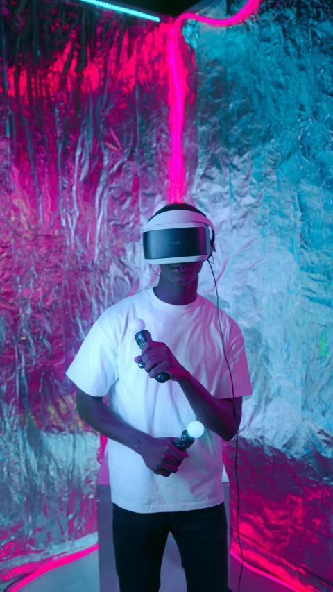 a man in a white shirt holding a video game controller, inspired by David LaChapelle, pexels, afrofuturism, with neon visor, virtual installation, wearing headset, hyper reali sm