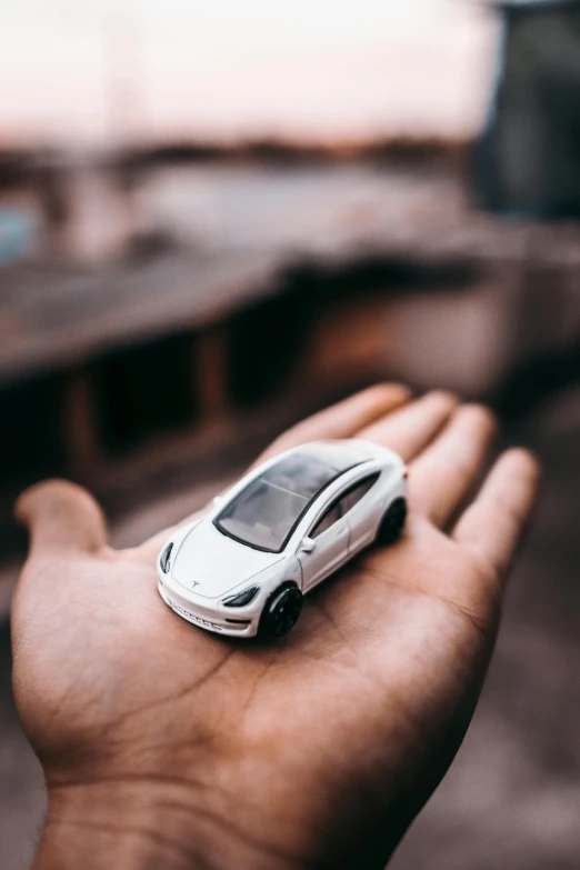 a person holding a toy car in their hand, pexels contest winner, tesla model 3, white pearlescent, thumbnail, architectural model