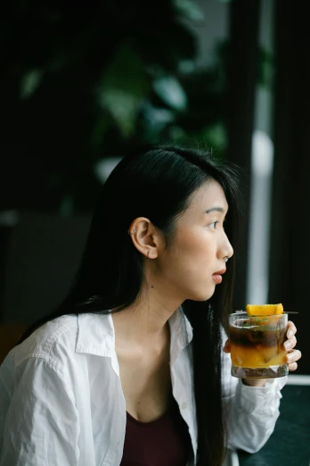 a woman sitting at a table with a drink in her hand, inspired by Tan Ting-pho, pexels contest winner, renaissance, wearing a white button up shirt, cold brew coffee ), profile view, korean woman