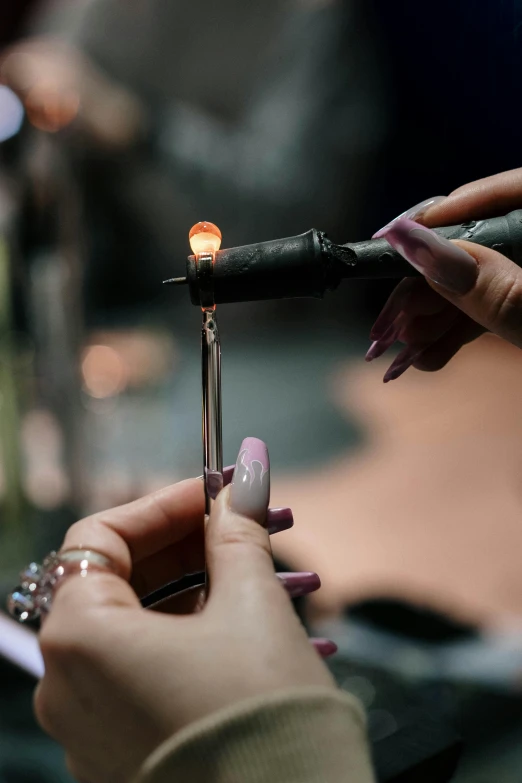 a close up of a person holding a lighter, renaissance, crystals enlight the scene, black oil bath, holding the elder wand, production photo