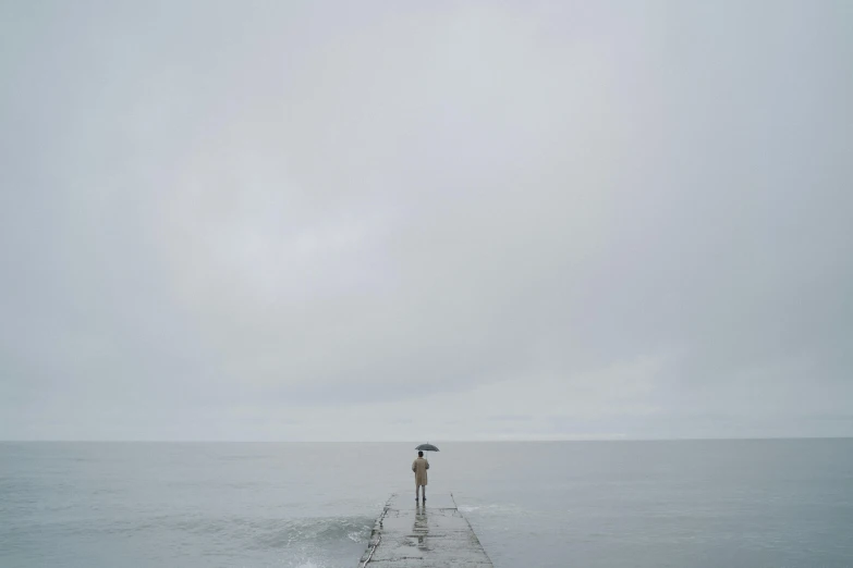 a person standing on a pier with an umbrella, inspired by Jan Rustem, minimalism, overcast gray skies, ignant, gray, concerned