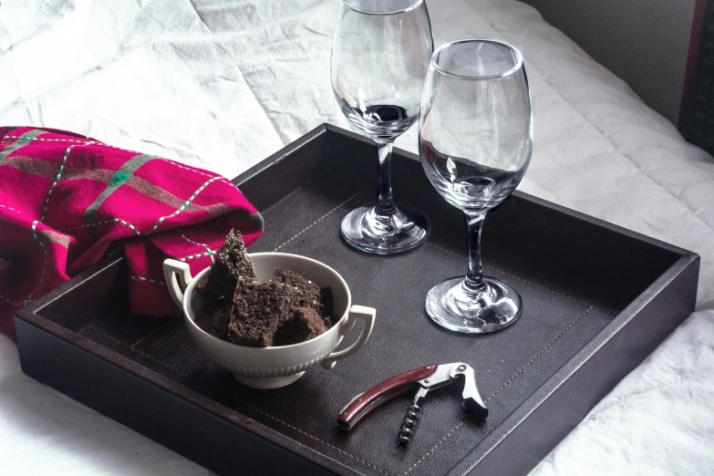 a tray with a bowl of food and two wine glasses, fully chocolate, spanners, square, uncropped