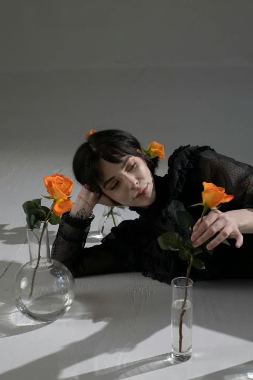 a woman laying on the ground next to vases of flowers, an album cover, by Winona Nelson, aestheticism, orange flowers, portrait androgynous girl, alice cullen, thinking pose