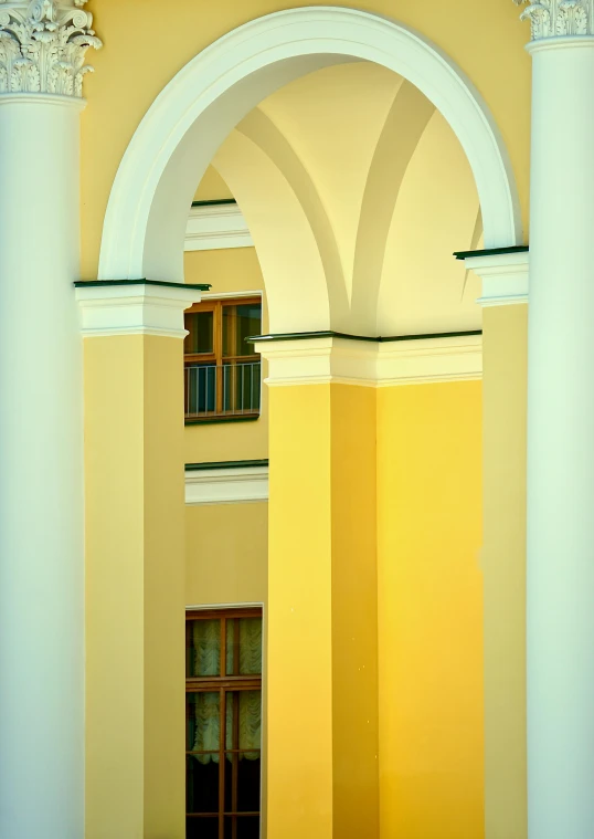 a clock mounted to the side of a yellow building, inspired by Ricardo Bofill, arabesque, arches adorned pillars, color image, square, high ceiling