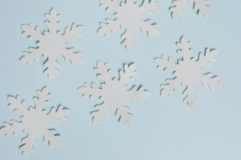 a close up of paper snowflakes on a blue surface, by Carey Morris, trending on unsplash, white background : 3, cozy wallpaper, background image, 5k