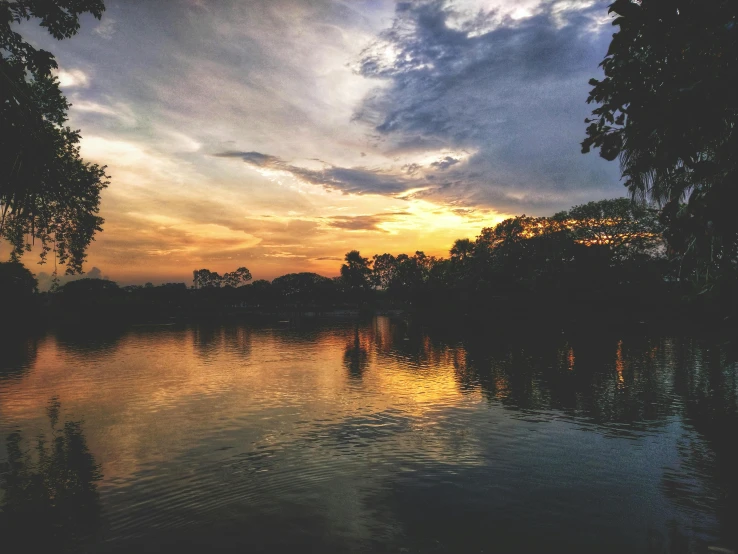 a body of water surrounded by trees under a cloudy sky, by Carey Morris, pexels contest winner, sunset panorama, with instagram filters, humid evening, cahaba river alabama