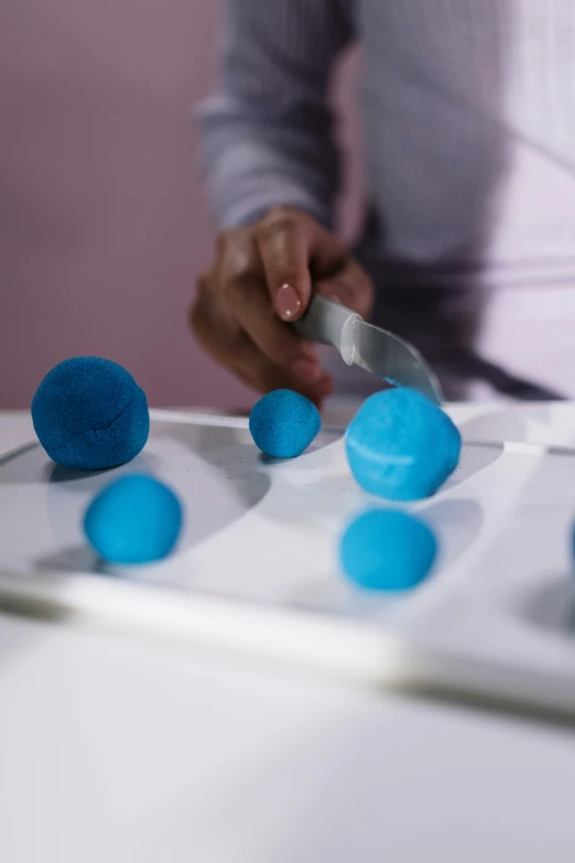 a close up of a person cutting doughnuts with a knife, inspired by Yves Klein, floating spheres and shapes, turquoise, modelling clay, tech demo