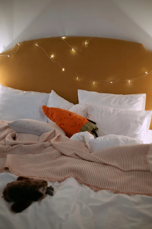 a couple of cats laying on top of a bed, light and space, fairy lights, orange and white color scheme, very comfy]