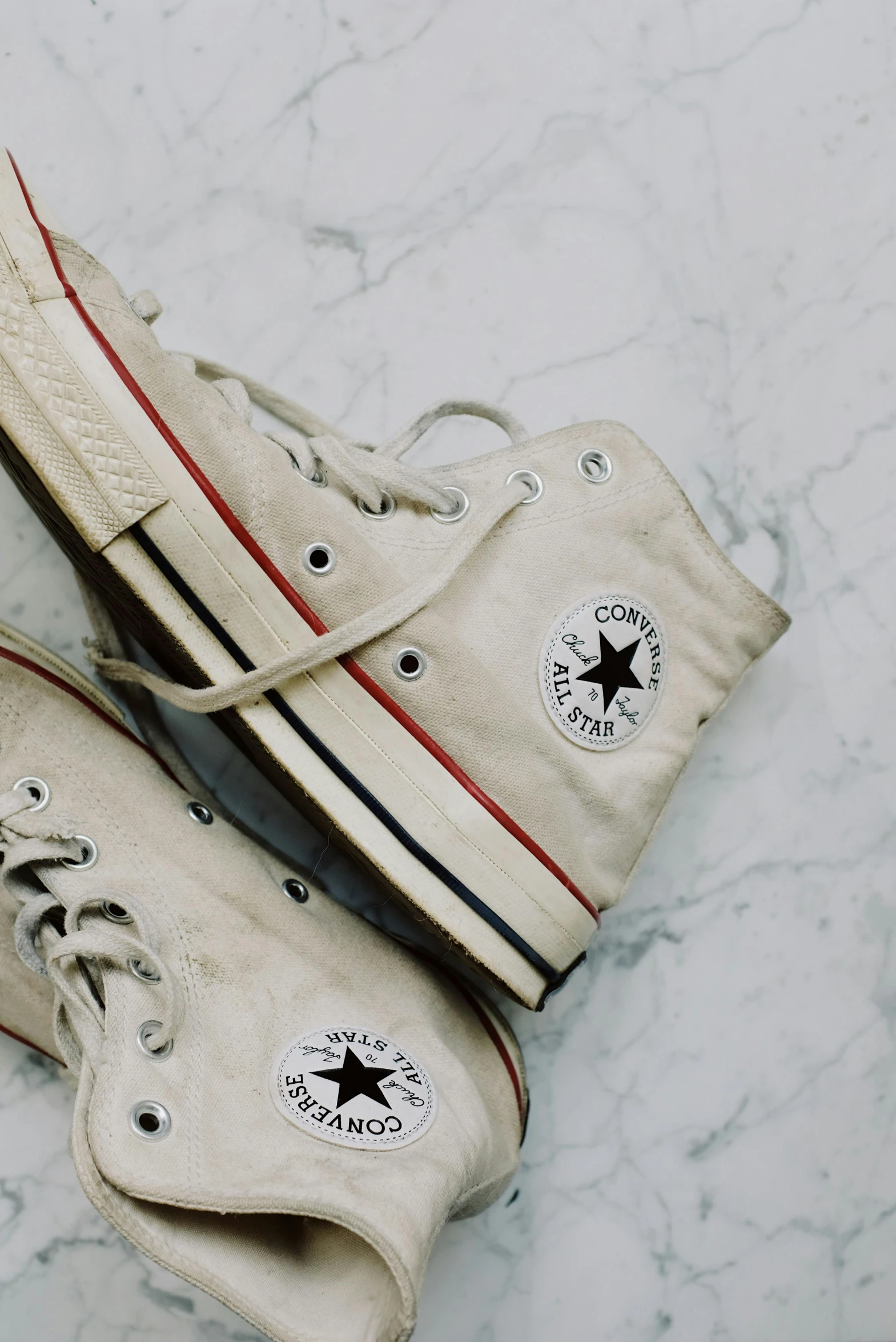 a pair of white converses on a marble surface, a colorized photo, trending on pexels, 1970's, made of marble, well preserved, white background