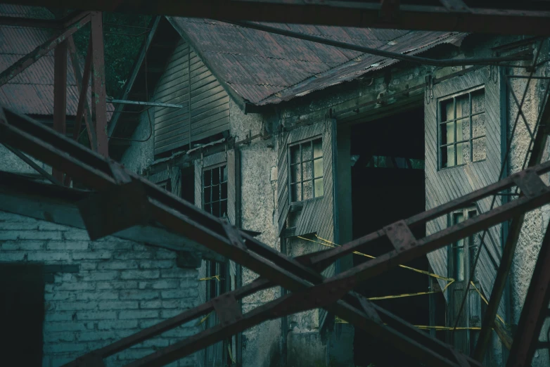 a close up of a metal structure near a building, a detailed matte painting, inspired by Elsa Bleda, pexels contest winner, old lumber mill remains, still from horror movie, dimly lit scene, old color photo