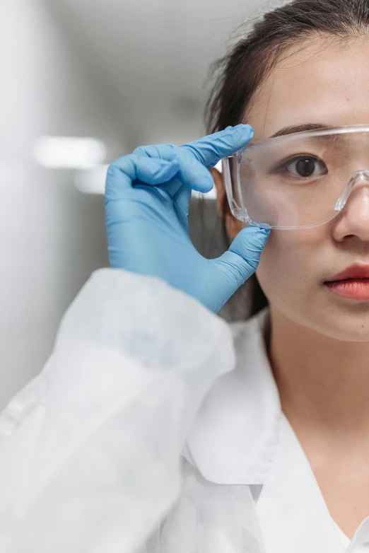 a woman in a lab coat and goggles talking on a cell phone, a picture, inspired by Feng Zhu, trending on pexels, wearing gloves, close up half body shot, looking serious, silicon and carbon