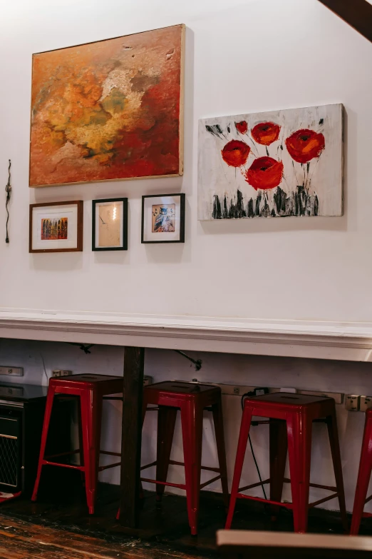 a room with red stools and paintings on the wall, trending on unsplash, sitting at the bar, red poppies, torches on wall, detail shot