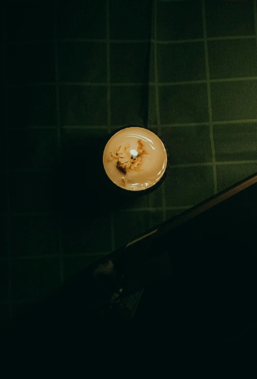 a lit candle sitting on top of a table, inspired by Elsa Bleda, swimming in a pool of coffee, overhead light, in a bar, top down extraterrestial view