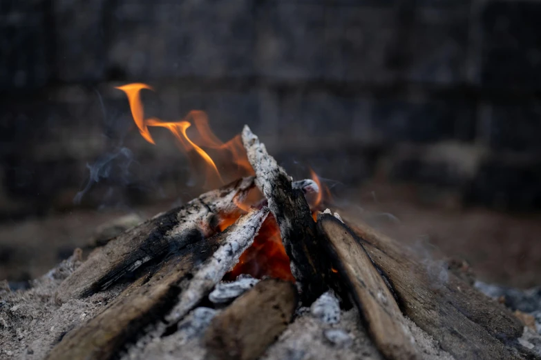 a close up of a fire with a brick wall in the background, pexels contest winner, camp fire, frying nails, a wooden, ignant