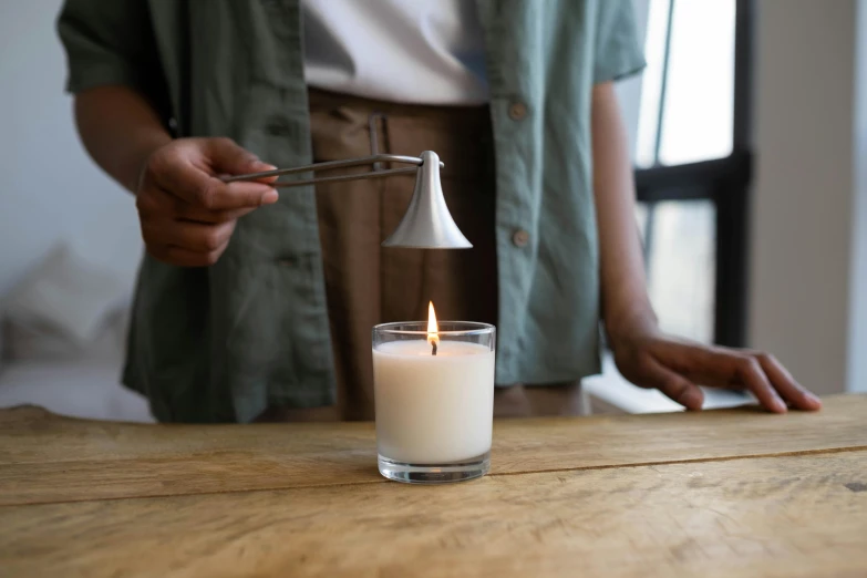 a person lighting a candle on a table, inspired by George Jamesone, unsplash, silver，ivory, soft volume absorbation, light cone, pouring