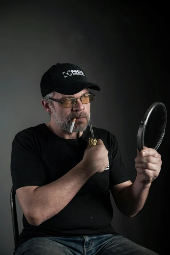 a man sitting in a chair holding a magnifying glass, inspired by Adriaen Hanneman, photorealism, with glasses and goatee, standing with a black background, standing in front of a mirror, profile picture 1024px