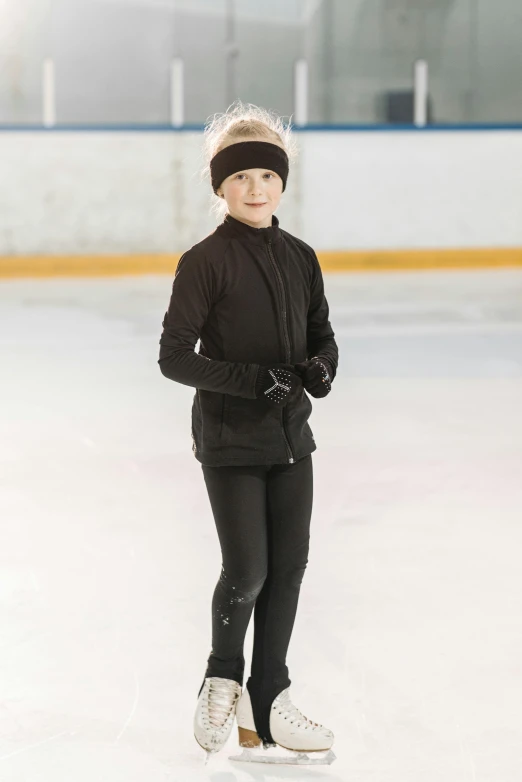 a woman is skating on an ice rink, jet black tuffle coat, wearing a track suit, for junior, main colour - black