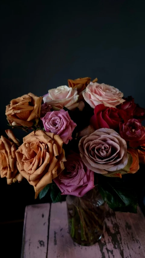 a vase filled with roses sitting on top of a wooden table, inspired by François Boquet, trending on unsplash, black and auburn colour pallet, close - up studio photo, multi colour, made of dried flowers