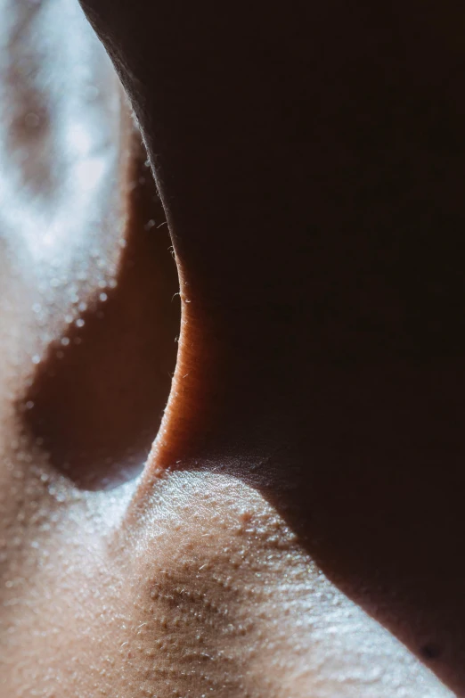 a close up of the back of a person's neck, a macro photograph, trending on pexels, visual art, noticeable tear on the cheek, brown body, high contrast of light and dark, inside a cavernous stomach