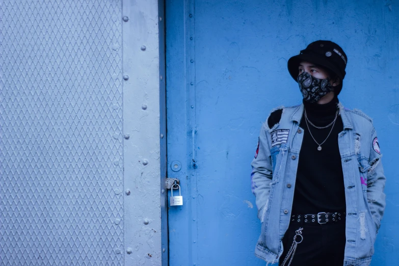 a man standing in front of a blue door, an album cover, unsplash, graffiti, black bandana mask, cybergoth, outfit: cop, double denim