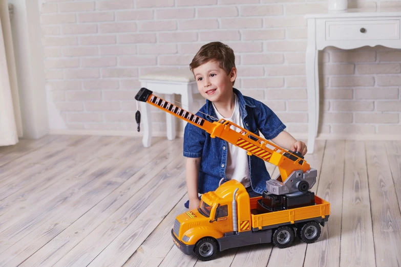 a young boy is playing with a toy truck, inspired by Sam Havadtoy, sitting in a crane, fully posable, 4yr old, official product photo