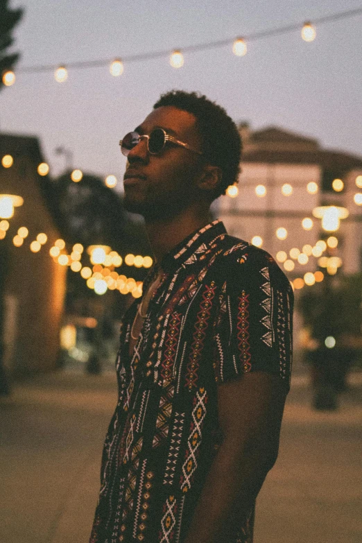 a man standing in the middle of a street at night, an album cover, by Stokely Webster, unsplash, renaissance, brown skinned, poolside, concert, california;