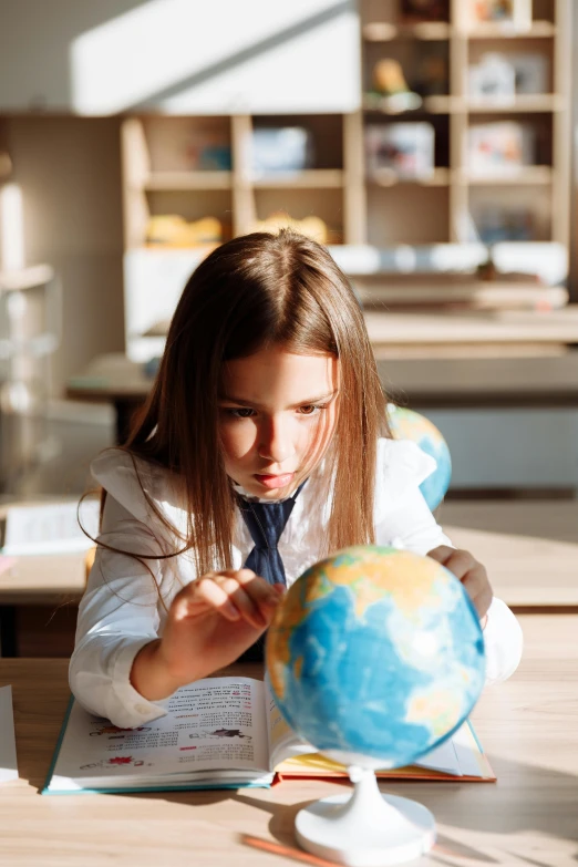 a little girl that is looking at a globe, a portrait, pexels contest winner, quito school, sat at a desk, gif, girl wearing uniform, slick design