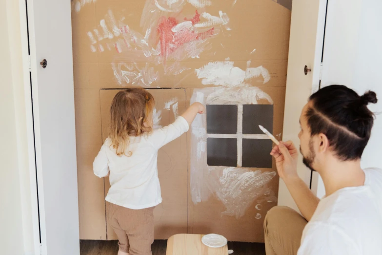 a man and a little girl standing in front of a cardboard door, a child's drawing, pexels contest winner, interactive art, painting on the ceiling, playing, white tracing, te pae