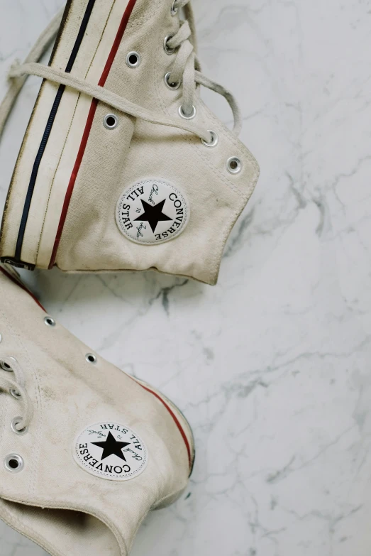 a pair of white sneakers sitting on top of a marble floor, trending on pexels, fine art, converse, bags on ground, vintage old, stars