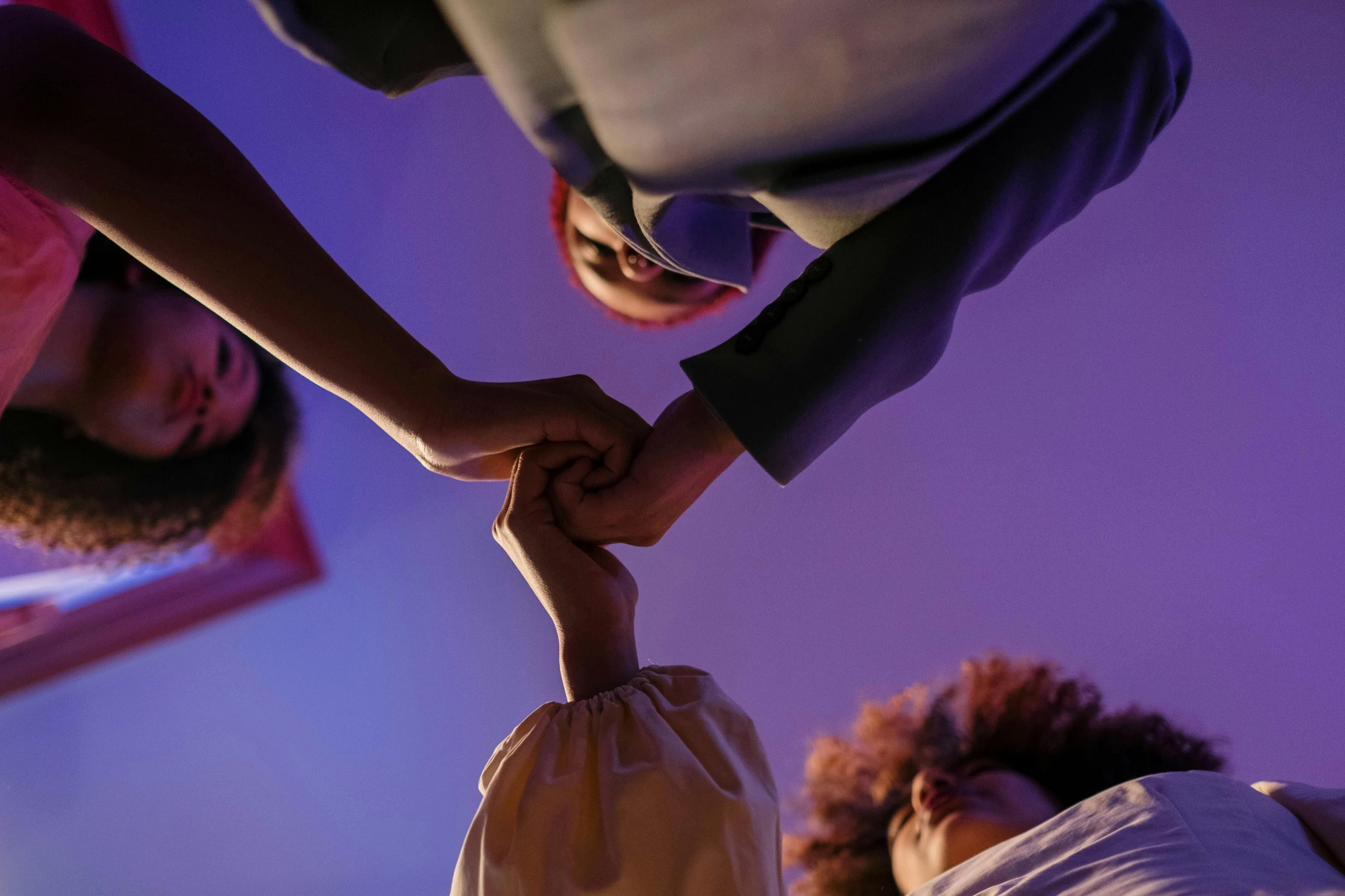 a group of people holding hands in a circle, an album cover, inspired by Georges de La Tour, unsplash, three women, low - angle shot, coloured, predawn