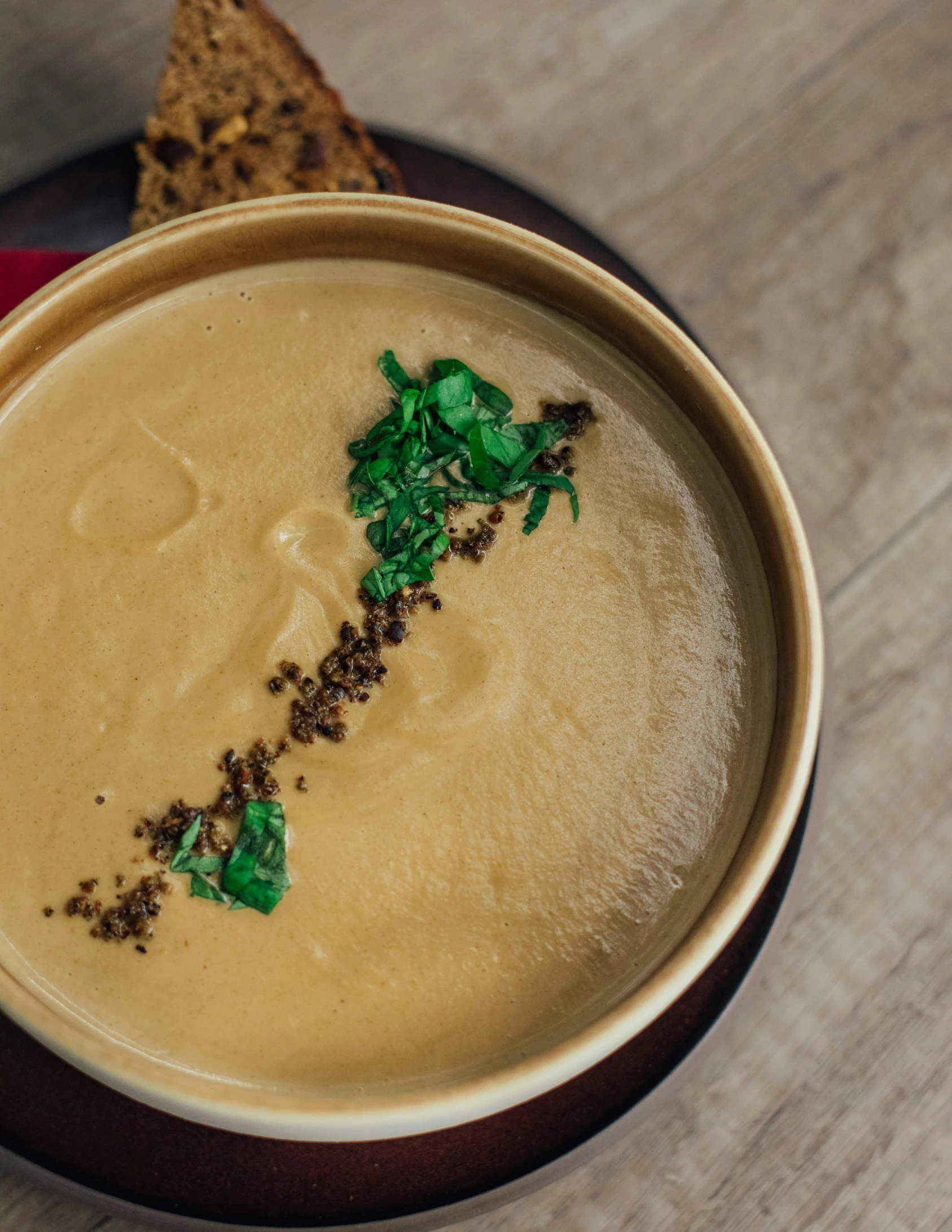 a bowl of soup sitting on top of a wooden table, cream of the crop, food particles, pots of gold, ginger