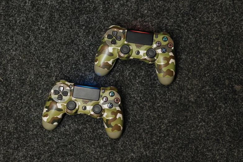 a couple of video game controllers sitting on top of a carpet, jungle camo, playstation 4, multicoloured, olive