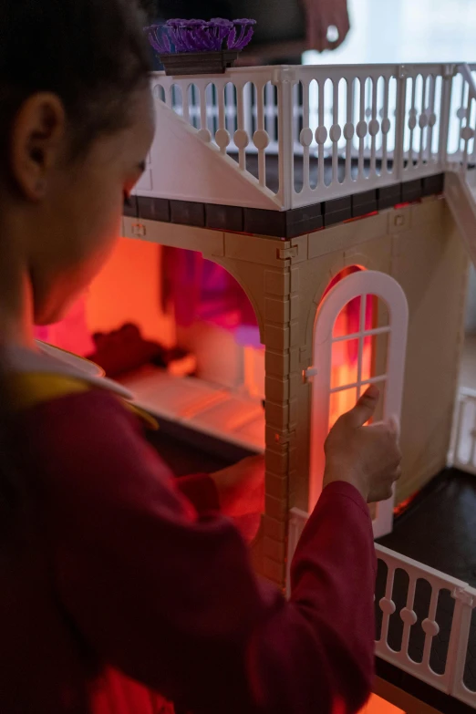 a little girl that is playing with a doll house, inspired by Hubert Robert, interactive art, orange and red lighting, bhutan, detail shot, buddhist monk