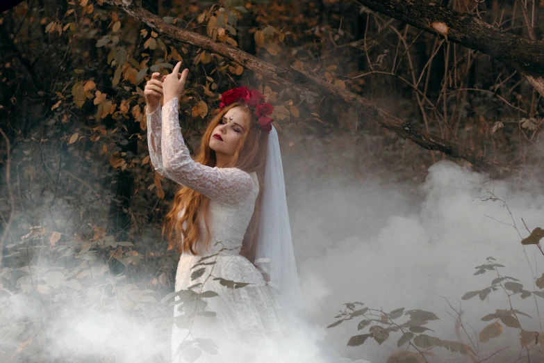 a woman in a wedding dress standing in smoke, taking a selfie, witch in the woods, her hands are red roots, with a white complexion