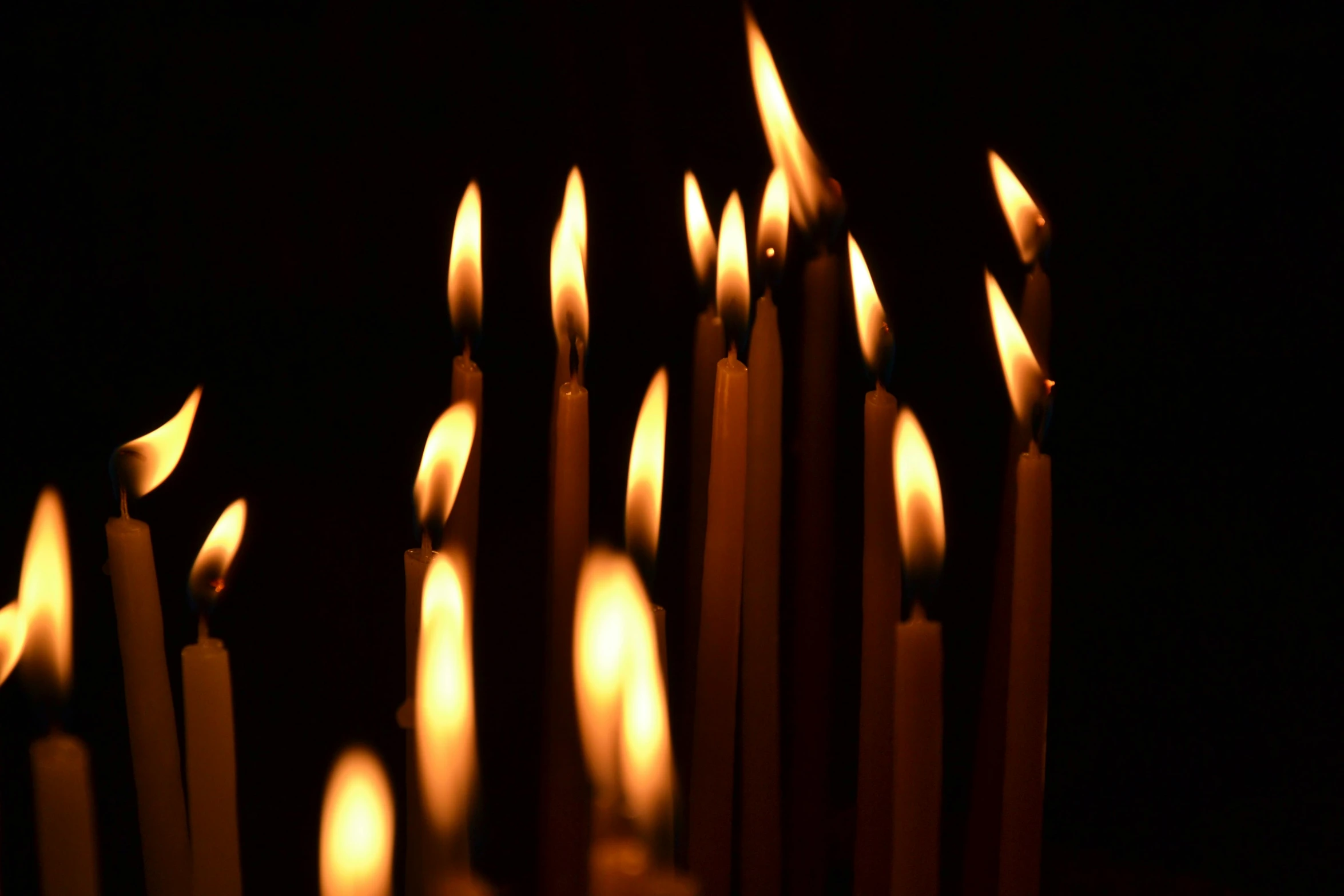 a group of lit candles sitting on top of a table, profile image, spears, with a black dark background, various sizes