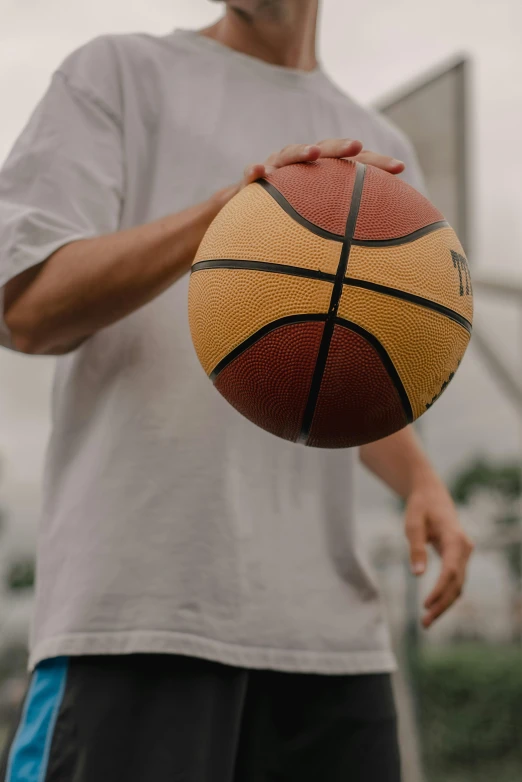 a man holding a basketball in front of a basketball hoop, zoomed out, zoomed in, cement, zoomed out to show entire image