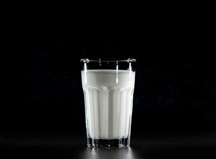 a glass of milk sitting on top of a table, inspired by Wlodzimierz Tetmajer, shutterstock, bauhaus, with a black background, background image, detailed product image, white