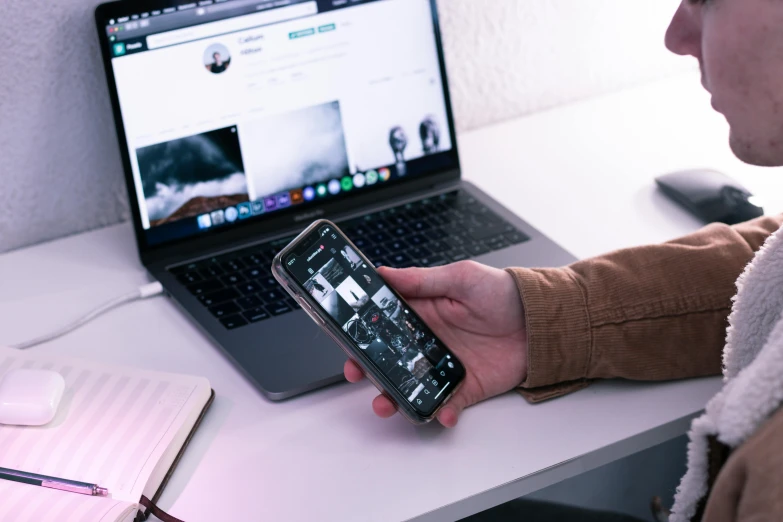 a person holding a cell phone in front of a laptop, a picture, trending on pexels, long shot view, 9 9 designs, tiktok, 555400831