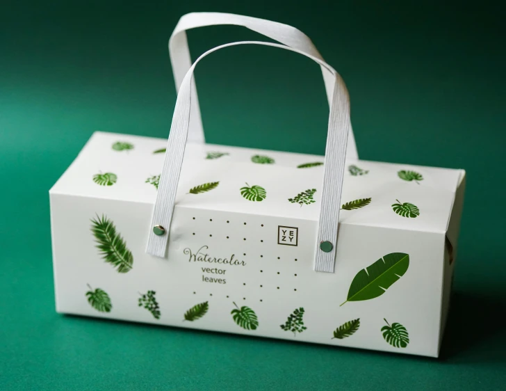 a white box with green leaves on it, in style of neodada, full of wonders, product display photograph, edible
