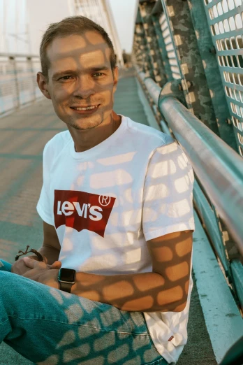 a man sitting on the side of a bridge, a picture, inspired by Louis Hersent, unsplash, happening, wearing a t-shirt, vintage levi ’ s ad, headshot profile picture, vitalik buterin