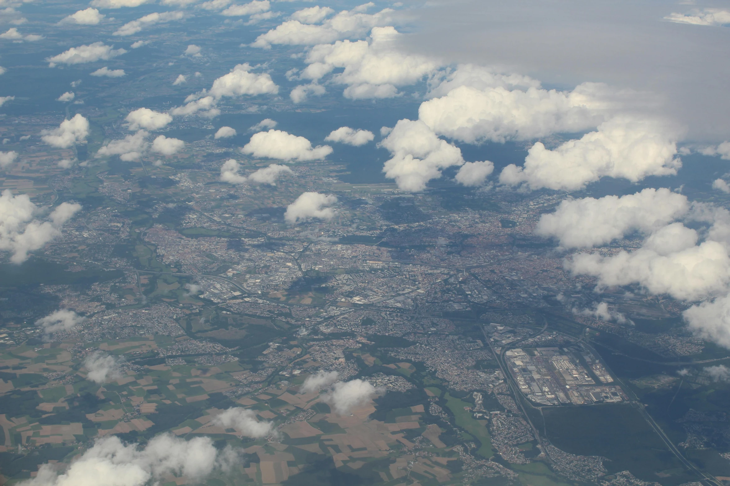 a view of a city from an airplane, by Niko Henrichon, pexels contest winner, hurufiyya, puffy cute clouds, nuremberg, highly detailed image, hd footage