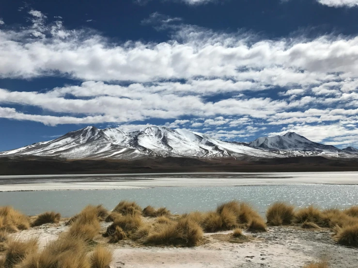 a body of water with a mountain in the background, a photo, salt dunes, quechua, avatar image, snowy plains